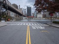 a empty street with a bridge over the river and an overpass at the end