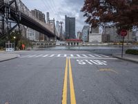 a empty street with a bridge over the river and an overpass at the end