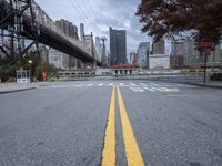 a empty street with a bridge over the river and an overpass at the end