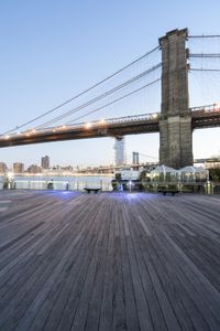 this is an outdoor boardwalk next to the water and a large bridge that is behind it