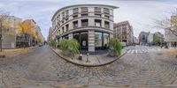 an empty street with buildings in the distance from a fish eye lens view taken while traffic crosses