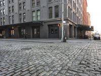 a building next to a sidewalk near two buildings that are on the same side of a road