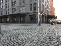 a building next to a sidewalk near two buildings that are on the same side of a road
