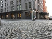 a building next to a sidewalk near two buildings that are on the same side of a road