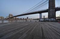 a view of brooklyn bridge and the boardwalk with boats nearby during the day, new york city