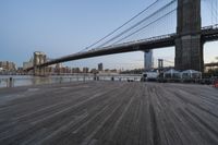 a view of brooklyn bridge and the boardwalk with boats nearby during the day, new york city