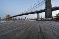 a view of brooklyn bridge and the boardwalk with boats nearby during the day, new york city