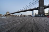 a view of brooklyn bridge and the boardwalk with boats nearby during the day, new york city