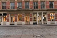 a store with a clock on it in a street next to building and cars behind it