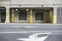 the outside view of the parking garage with three empty doors and some yellow arrows on the ground