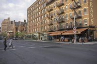 a busy street in a city area next to tall buildings with red and white awnings