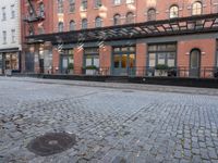 a red fire hydrant sitting in the middle of a brick street and next to tall buildings