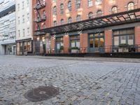 a red fire hydrant sitting in the middle of a brick street and next to tall buildings