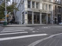 an intersection of a city street with a pedestrian walking by the street and a building