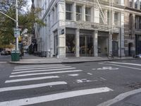 an intersection of a city street with a pedestrian walking by the street and a building