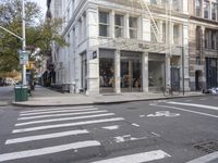 an intersection of a city street with a pedestrian walking by the street and a building