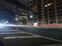 a blurry photo of a city street at night with tall buildings and lights in the background