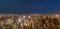 the city at night with a blue sky in the background as seen from the top of rockefeller