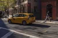 yellow taxi cab sitting on the side of the road with people walking on either side