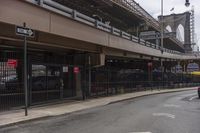 an intersection under a bridge that has a car parked on the side of the street