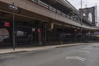 an intersection under a bridge that has a car parked on the side of the street