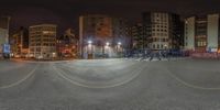 a photo of a man in the middle of a street at night with an empty parking lot near the city