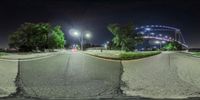 view from an inside fish - eye lens at night of an amusement park with an amusement roller coasterr in the distance