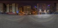 a 360 - fish eye view of a city at night with people standing at the roadside, some cars on the road