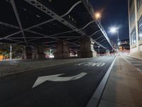 a car passes under the highway under an overpass at night, with light trails coming from underneath