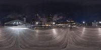 the skateboarding ramp on a nighttime city skyline view is circular and is empty as night approaches