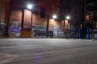 a graffiti covered building at night in a street corner with no traffic or people on it