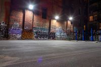 a graffiti covered building at night in a street corner with no traffic or people on it