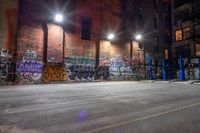 a graffiti covered building at night in a street corner with no traffic or people on it