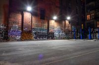 a graffiti covered building at night in a street corner with no traffic or people on it