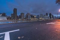 an empty road on a city street near the water at night, with streetlights glowing down