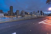an empty road on a city street near the water at night, with streetlights glowing down