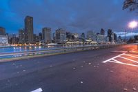 an empty road on a city street near the water at night, with streetlights glowing down