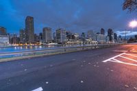 an empty road on a city street near the water at night, with streetlights glowing down