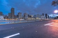 an empty road on a city street near the water at night, with streetlights glowing down
