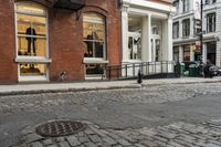 two people walk through an alley near brick buildings on a city street with car parking spaces