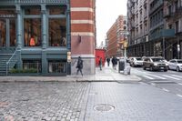 a view down the street, looking toward the storefront from the corner at pedestrians
