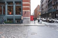 a view down the street, looking toward the storefront from the corner at pedestrians