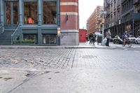 a view down the street, looking toward the storefront from the corner at pedestrians
