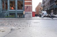 a view down the street, looking toward the storefront from the corner at pedestrians