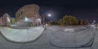 a 360 lens of a street at night with trees and lights on the ground and buildings in the background