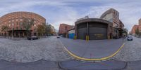 a fisheye view showing the intersection of a street with a car parked at it and a large building in the distance