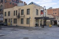 a street scene with an old yellow brick building and cars parked in front of it