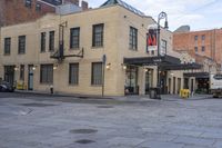 a street scene with an old yellow brick building and cars parked in front of it