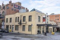 a street scene with an old yellow brick building and cars parked in front of it