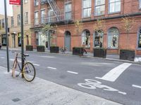 a bicycle is parked on the side of the street in front of a large brick building